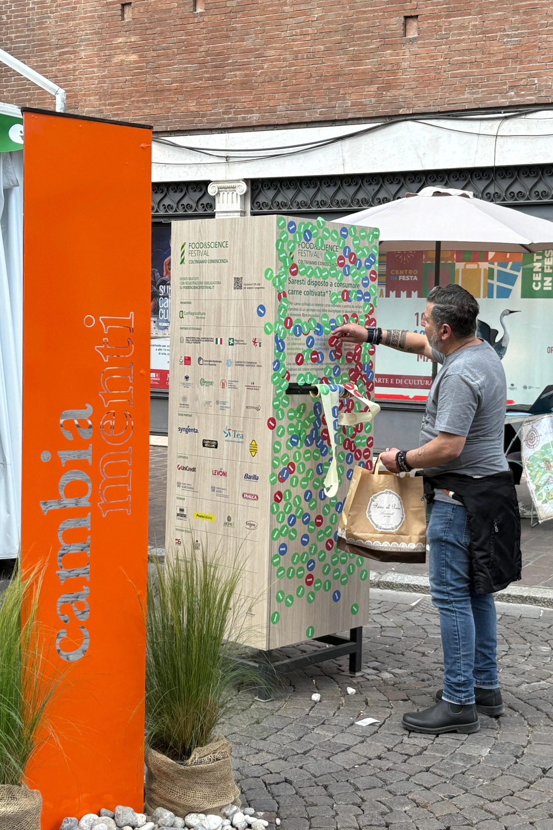 installazione 2025: un passante attacca l'adesivo del colore della sua risposta sul totem interattivo