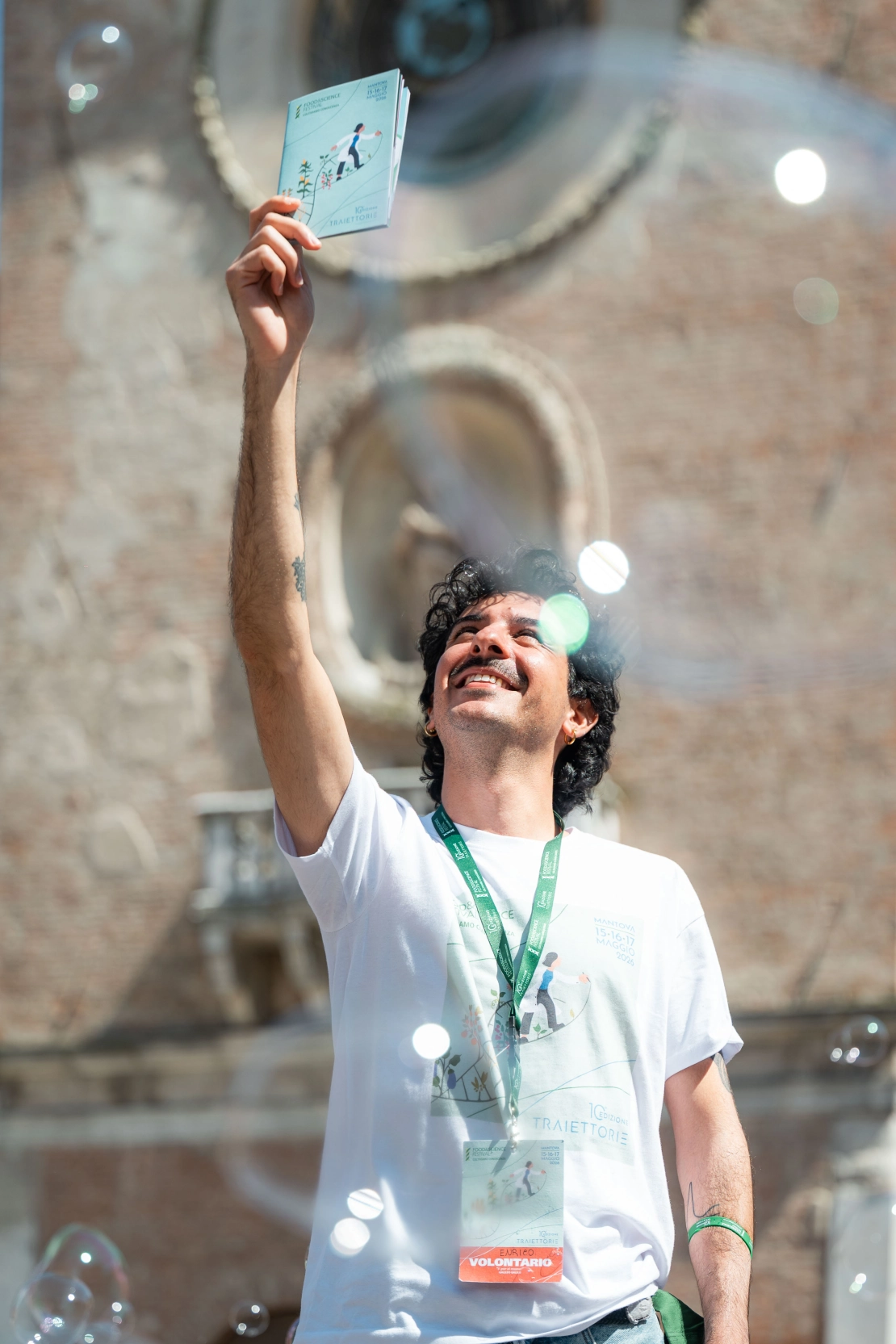 un volontario mostra il libretto e il badge davanti alla Torre dell'Orologio