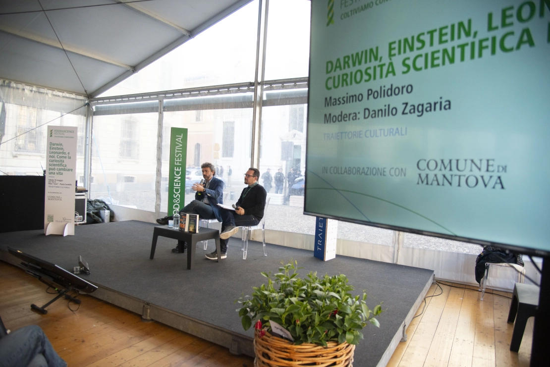 due relatori parlano dal palco principale sotto la tensostruttura in piazza Sordello